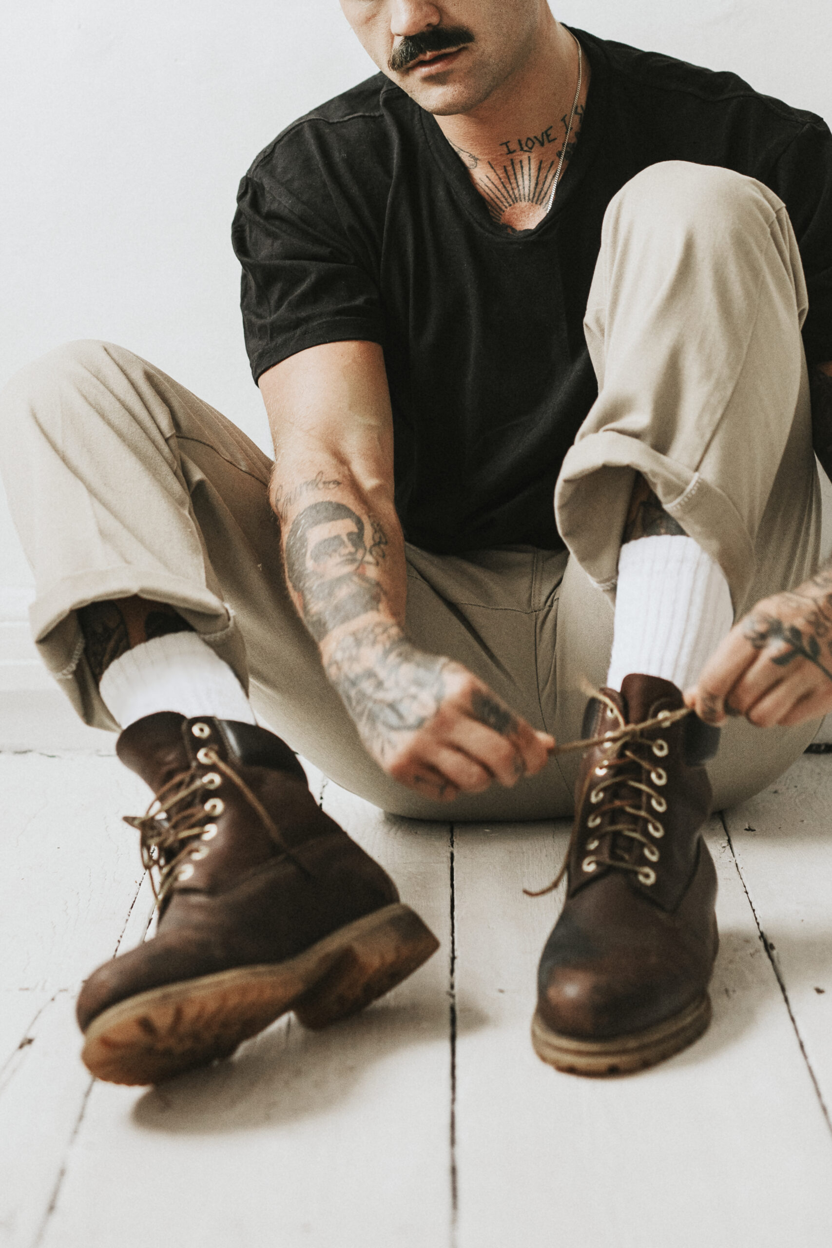 Alternative man tying boots shoelaces on the floor